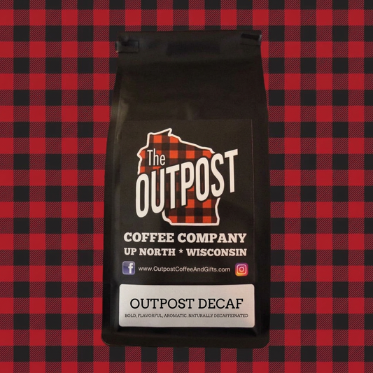 Outpost Decaf coffee bag on red and black plaid, labeled bold, flavorful, aromatic, naturally decaffeinated